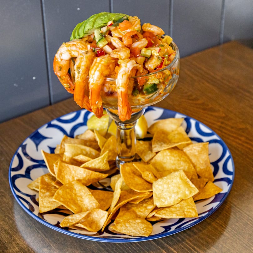 Guatemalan shrimp ceviche cocktail with avocado and tortilla chips on a blue and white plate.