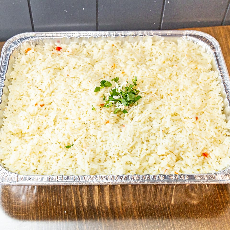 Large aluminum tray filled with white rice, garnished with fresh cilantro and shredded cheese.